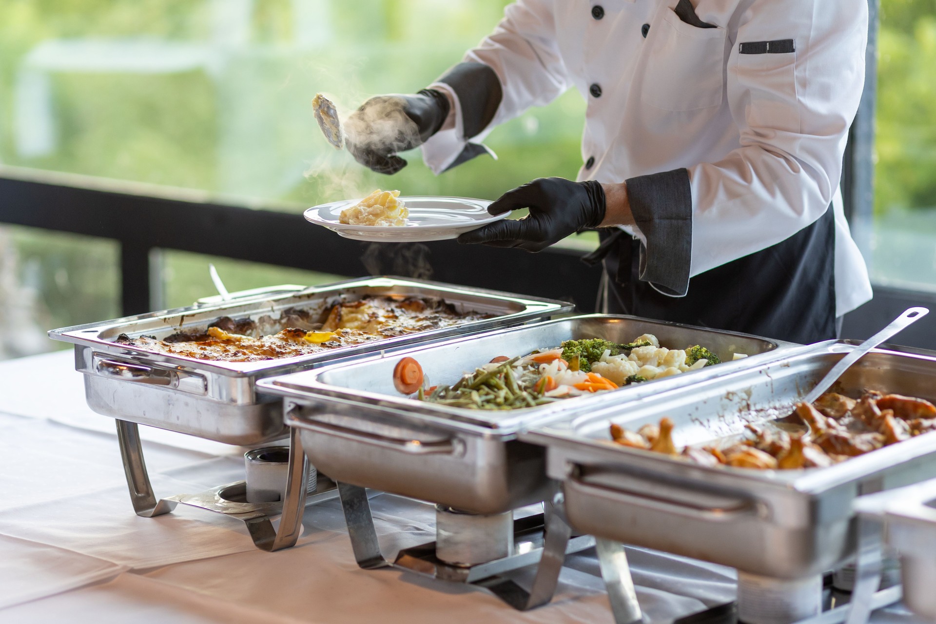 Chef serving a variety of delicious dishes at a catered event in a modern venue during midday
